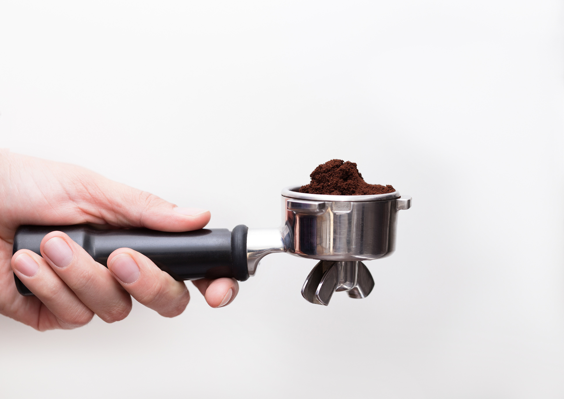Man is using a tamper to press freshly ground coffee